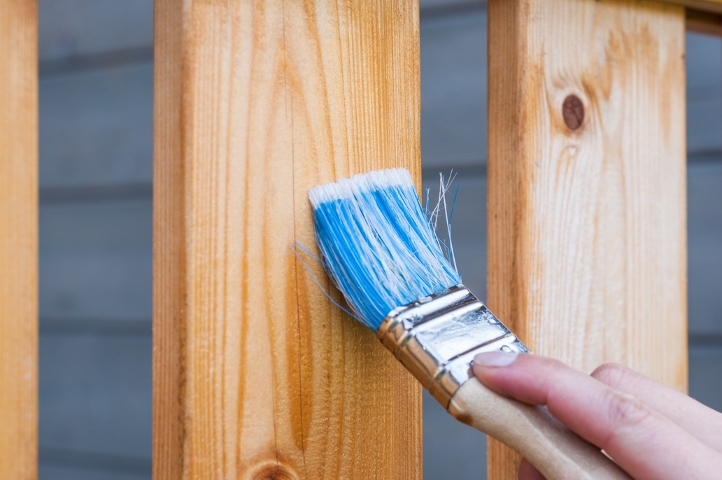Paint brush painting wooden fence 